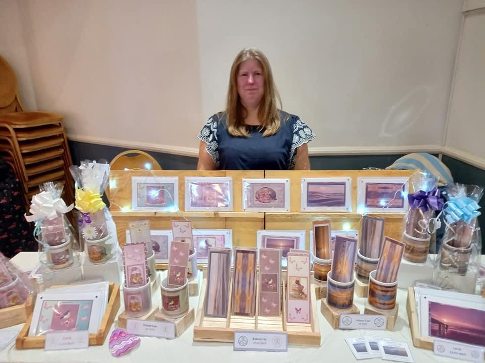 Marie stood behind her fist craft market stall - will a beautiful display of cards, photos, and gift sets laid out infront of her.